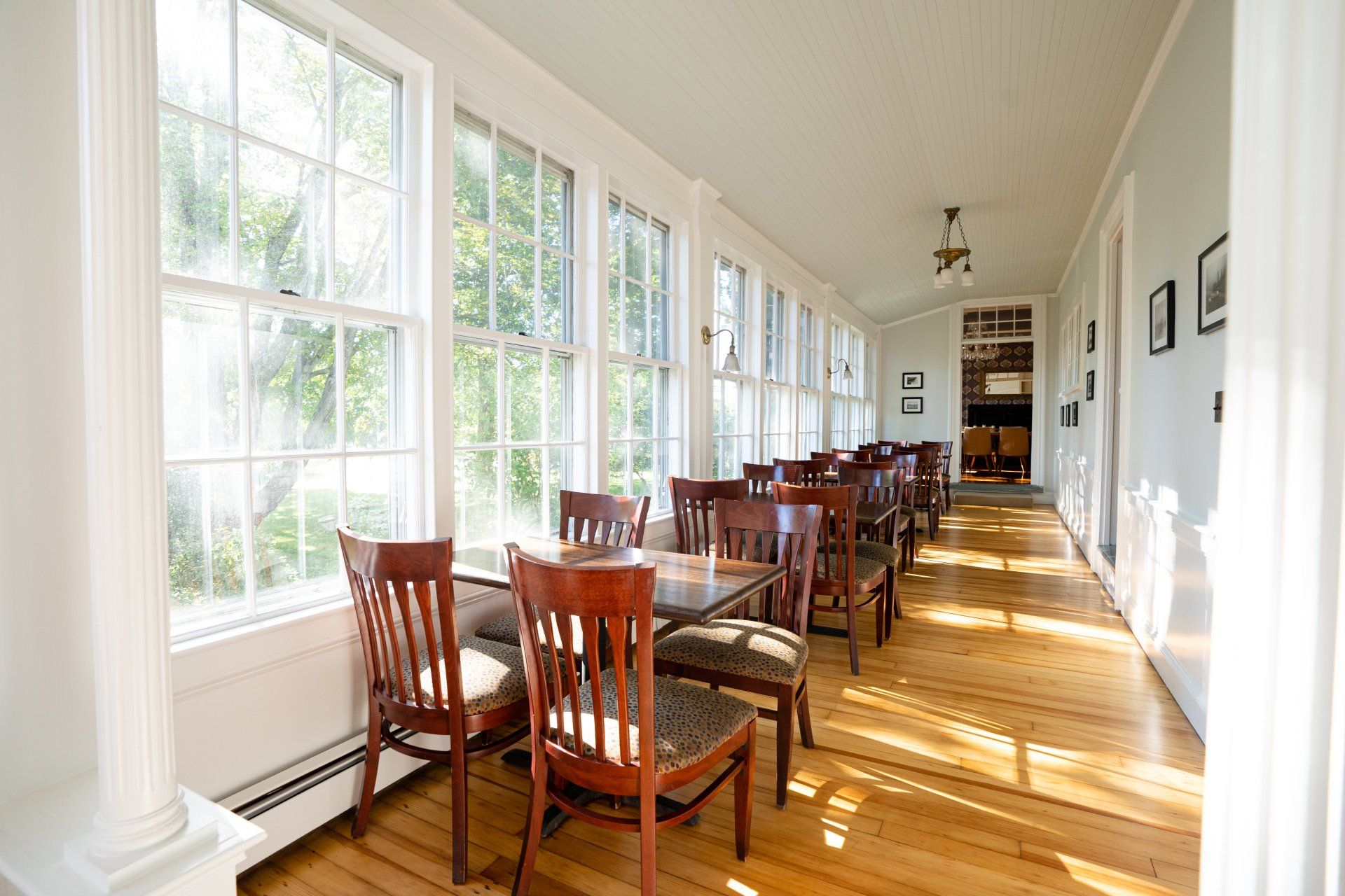 A long hallway with tables and chairs and lots of windows