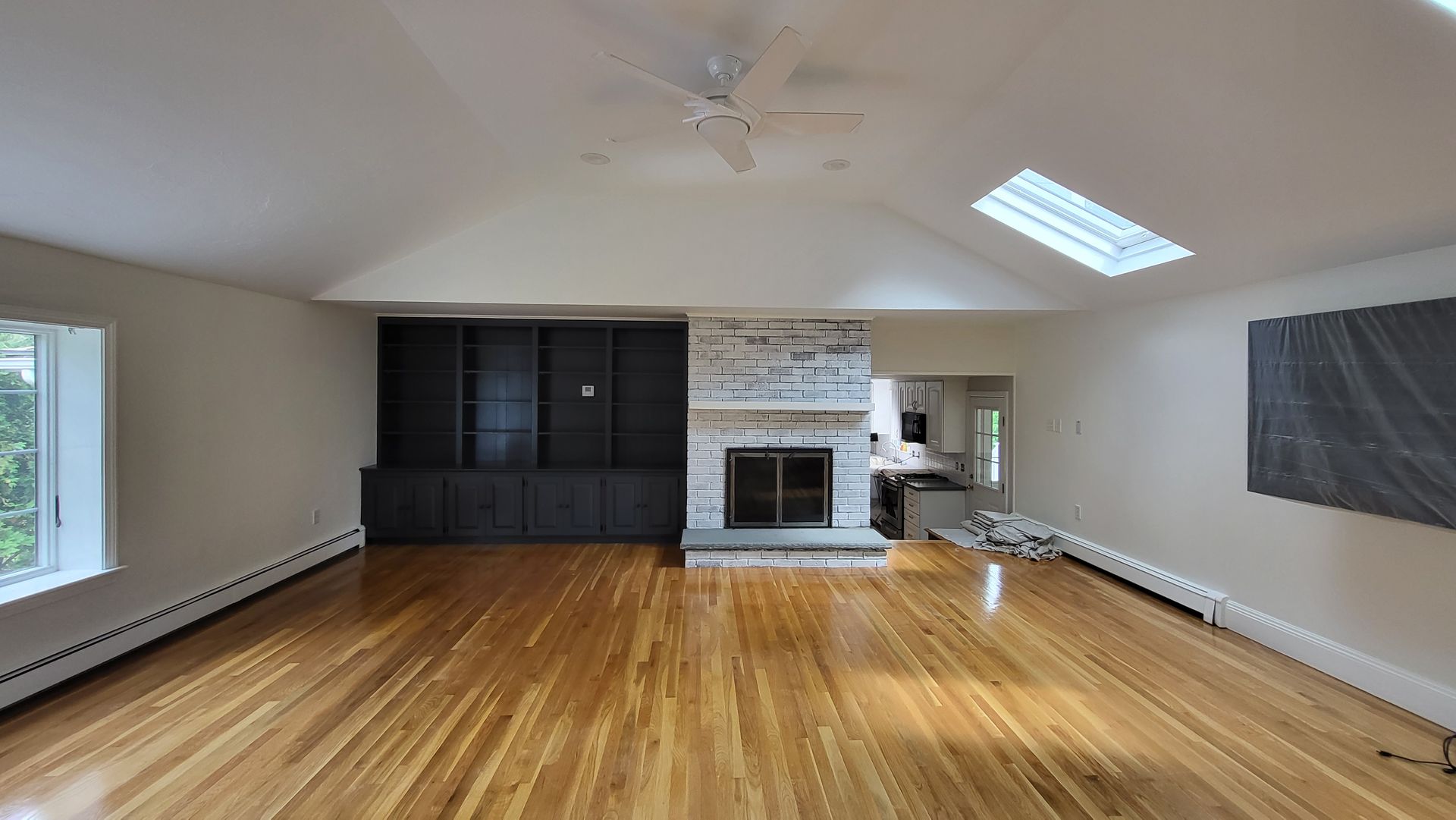 An empty living room with hardwood floors and a fireplace.