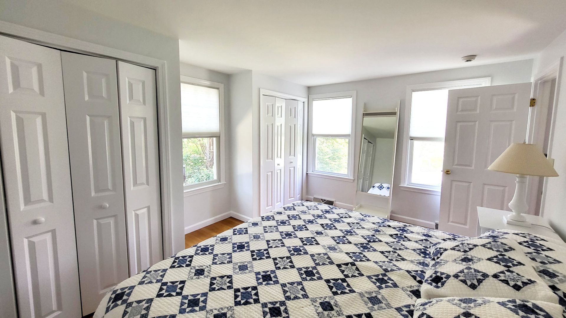 A bedroom with a bed , closets , and a mirror.