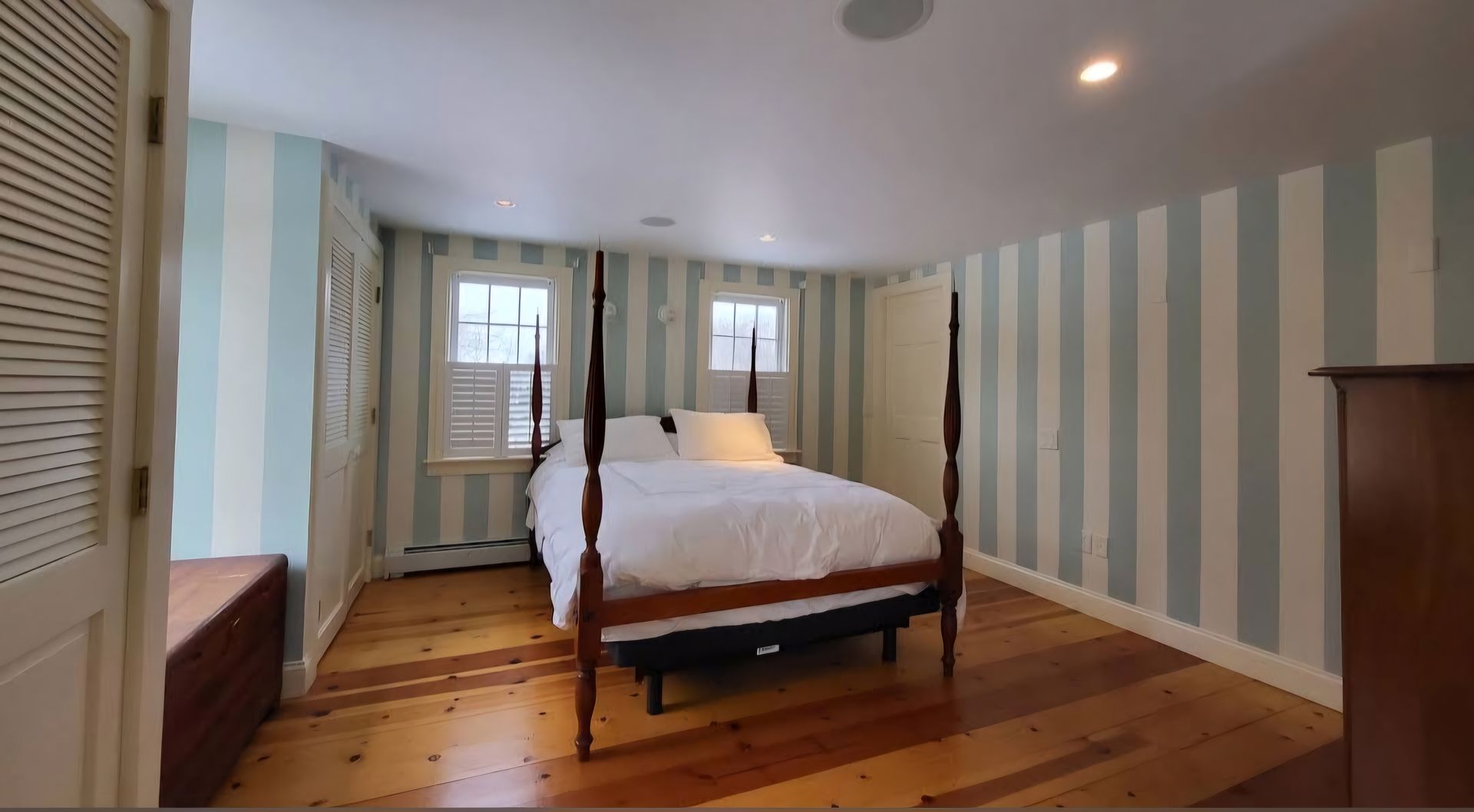 A bedroom with striped walls and a four poster bed