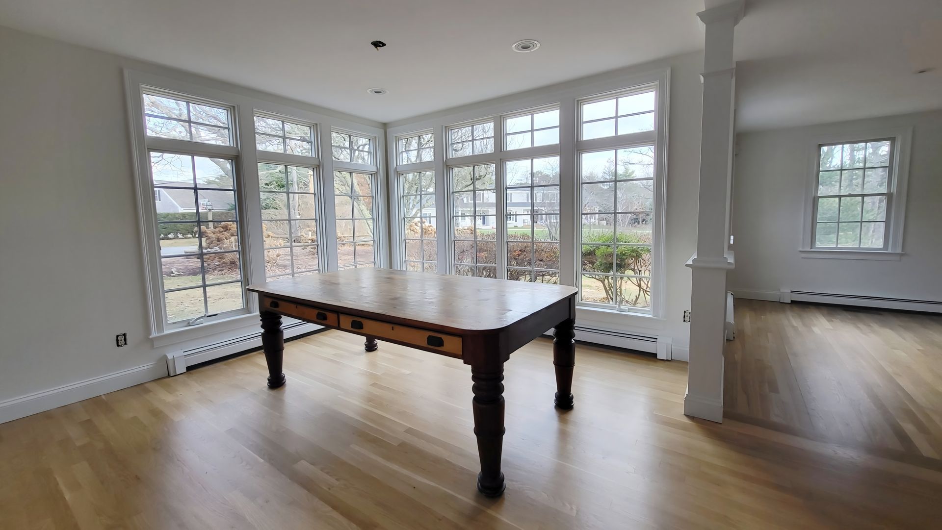 There is a table in the middle of the room with a lot of windows.