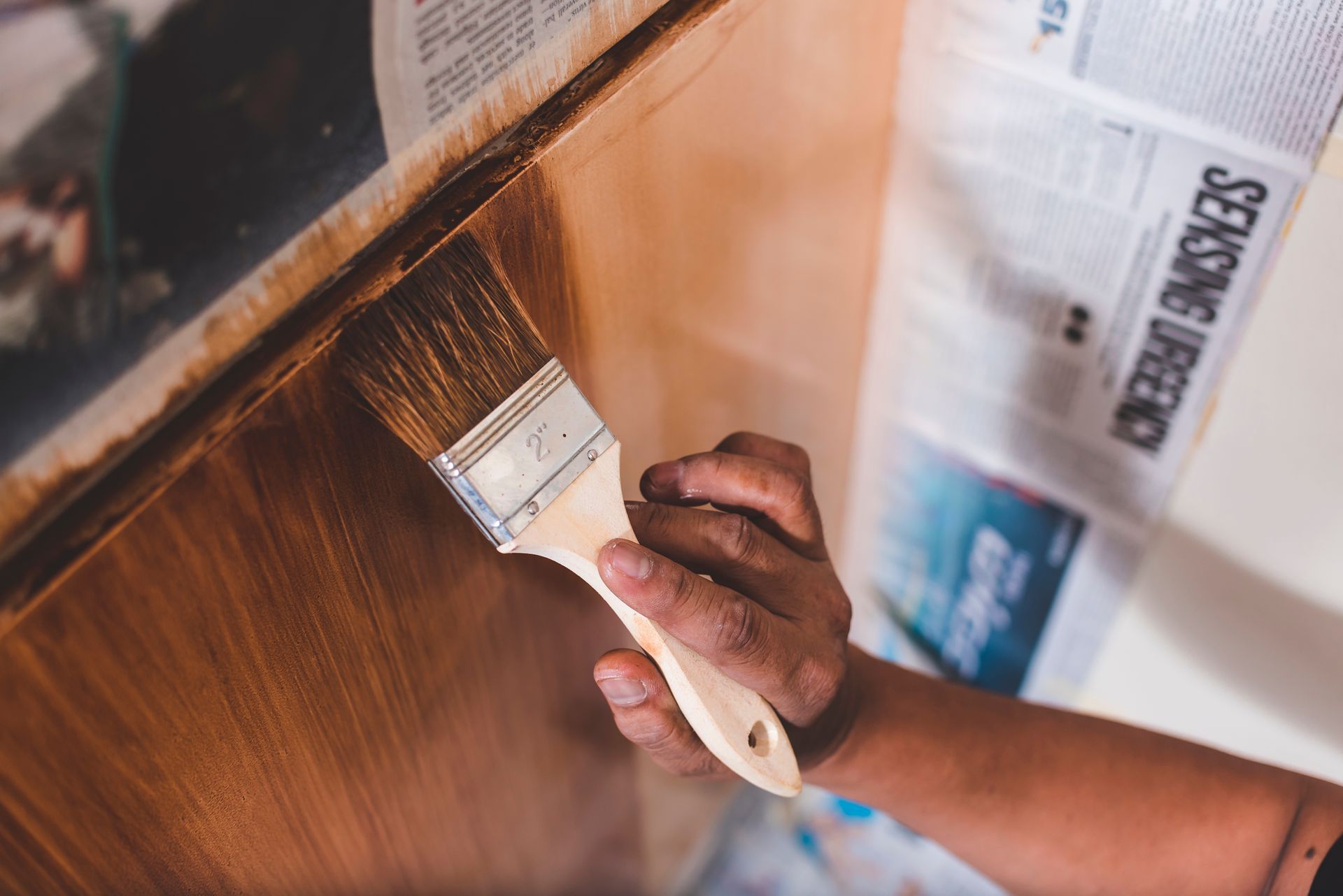 A person is painting a wooden surface with a brush.