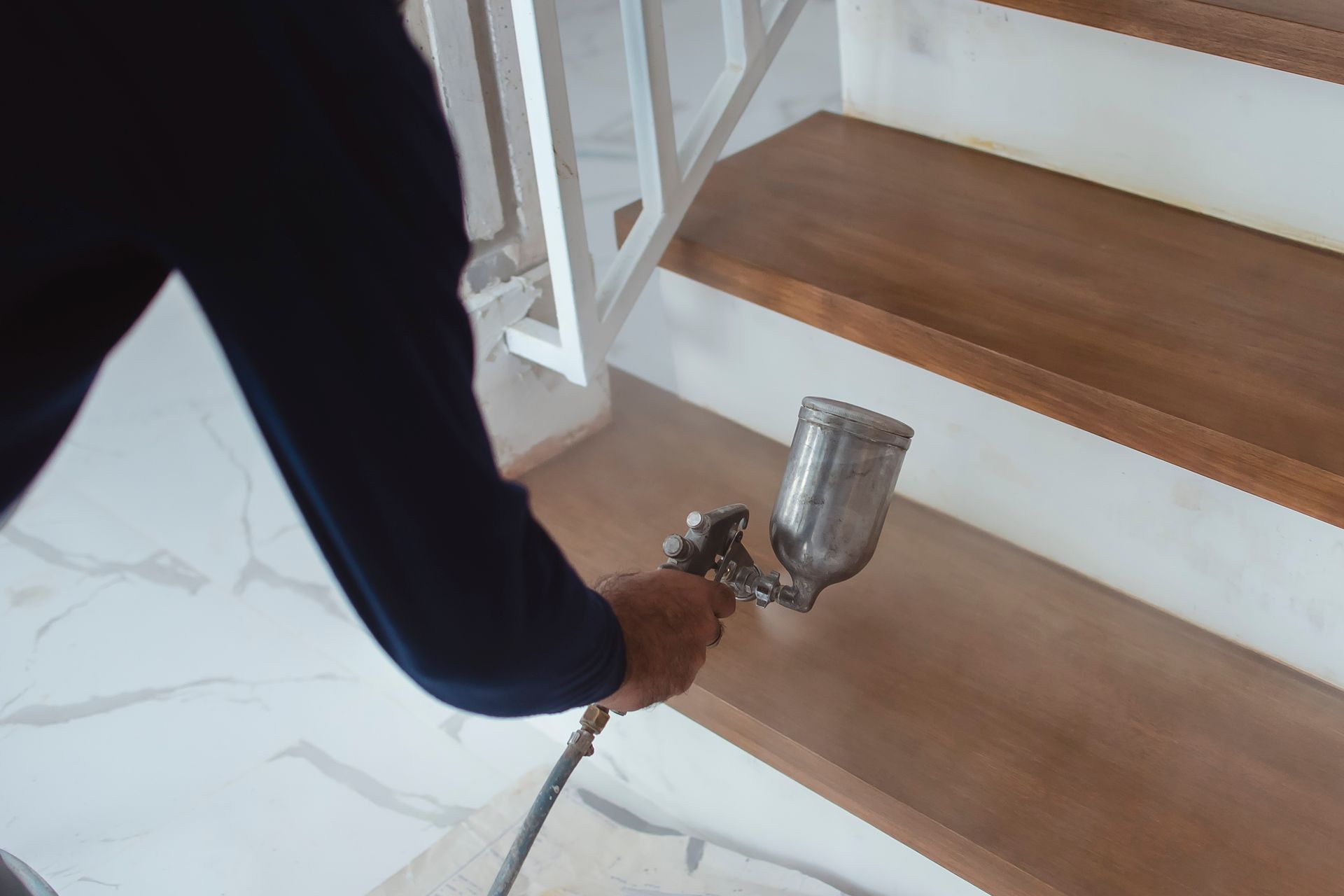 A person is spraying paint on a wooden staircase.