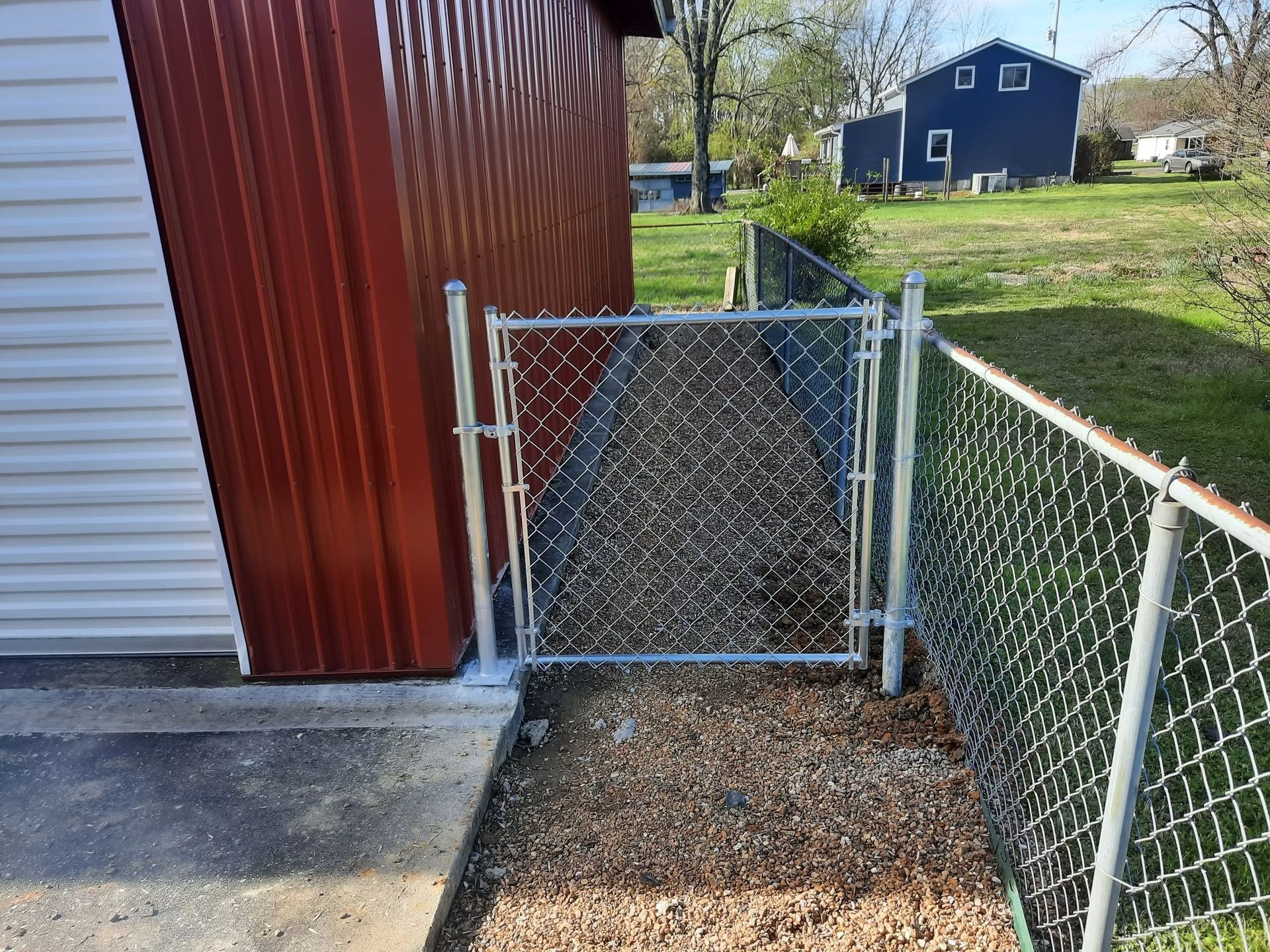 A chain link fence with a gate in front of a barn.