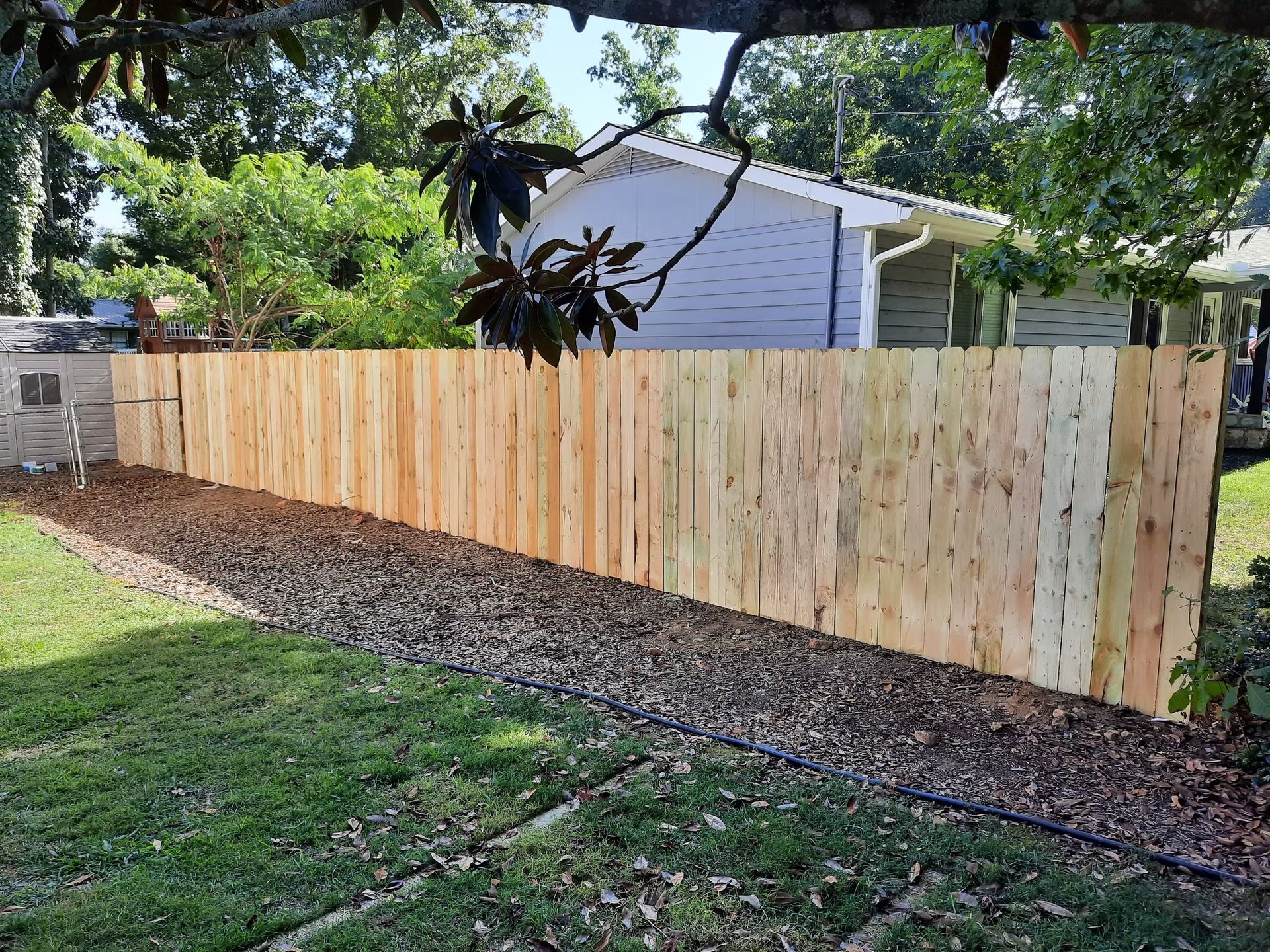 A wooden fence is in the backyard of a house.