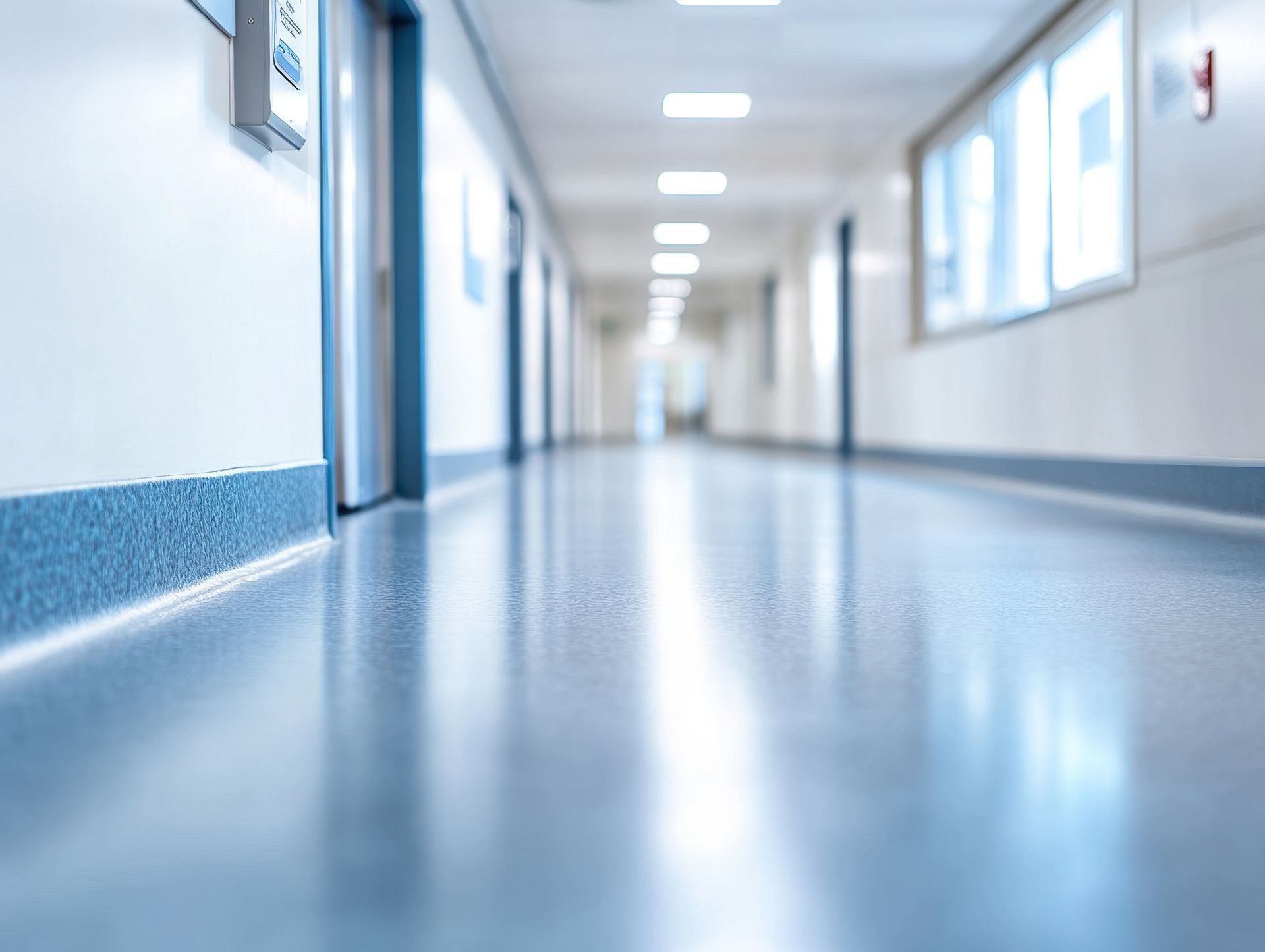 A hospital hallway with a blue floor and white walls.