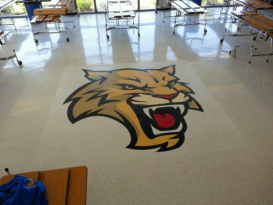 A tiger 's head is painted on the floor of a cafeteria
