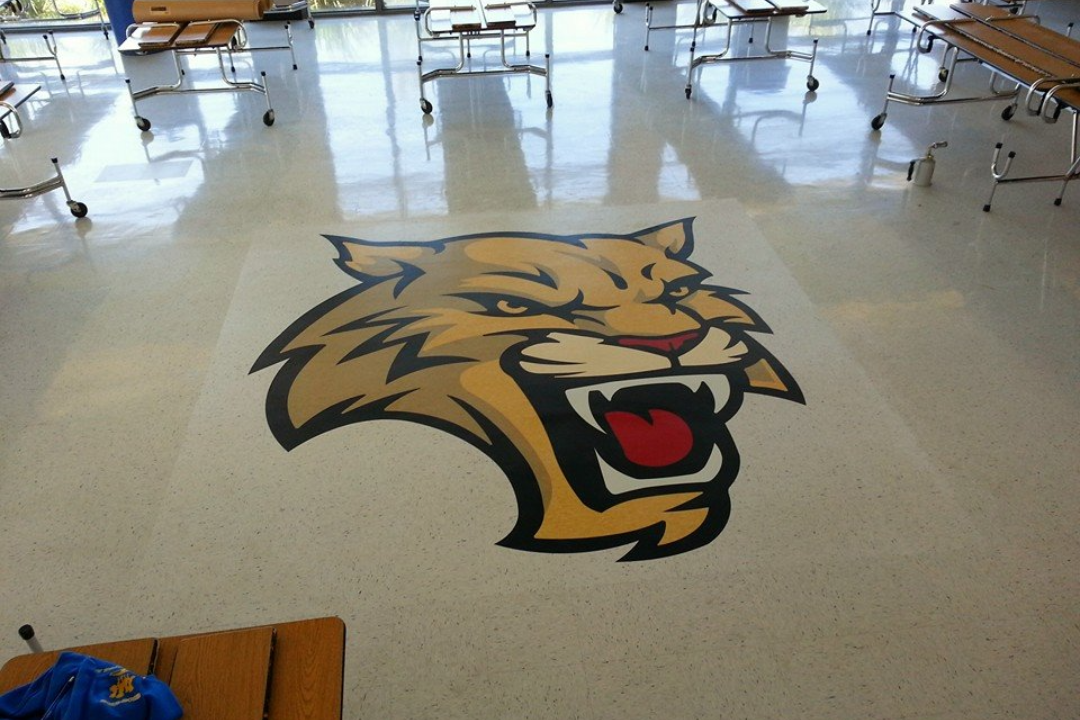 Bobcat logo on a school cafeteria floor, surrounded by tables.
