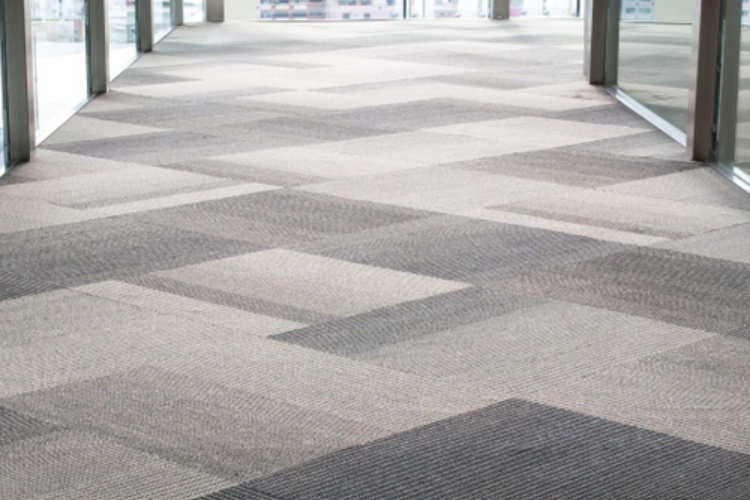A person using an orange floor buffer in a large, shiny hallway.