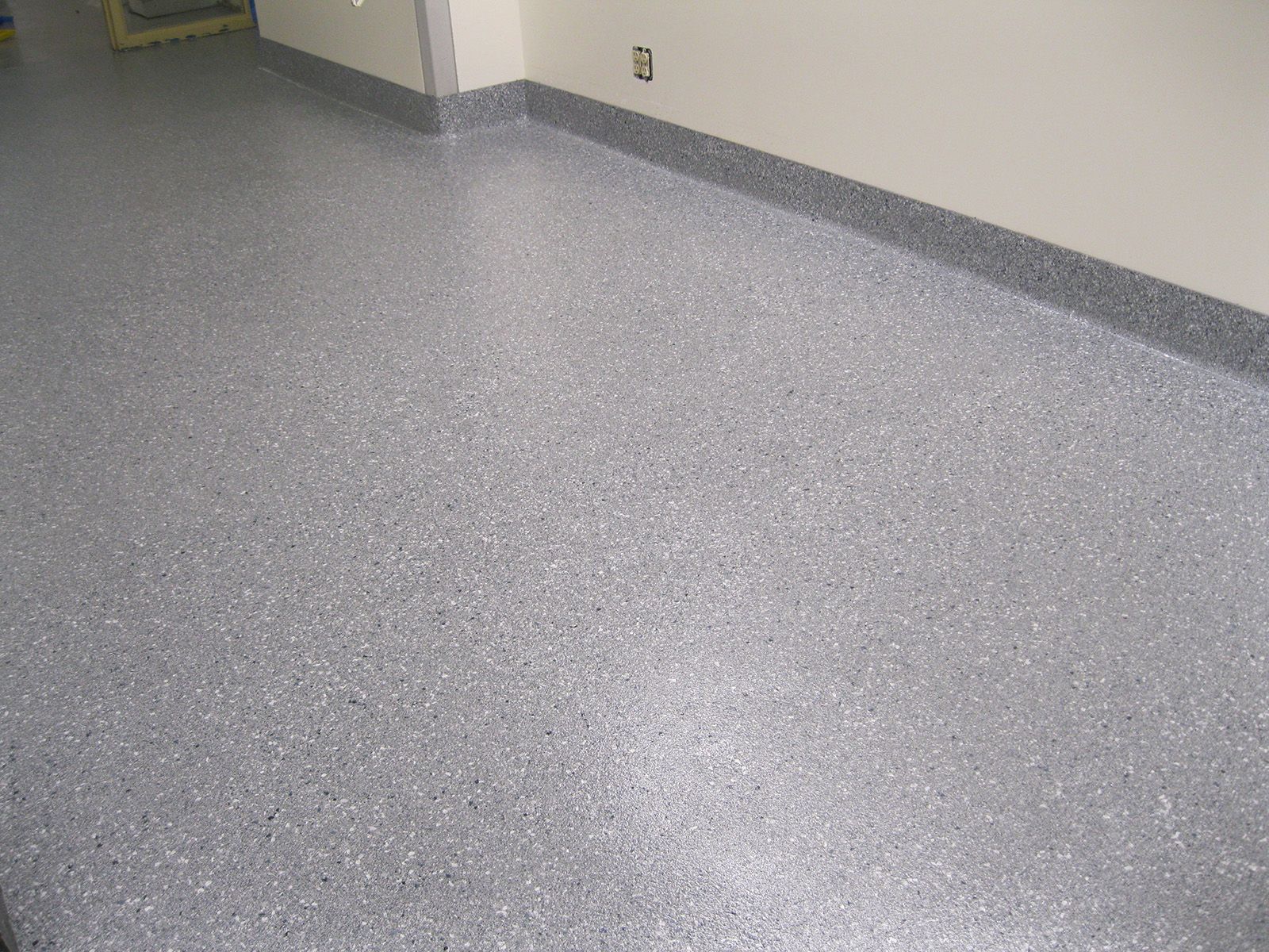 A gray floor with a white wall in a room.