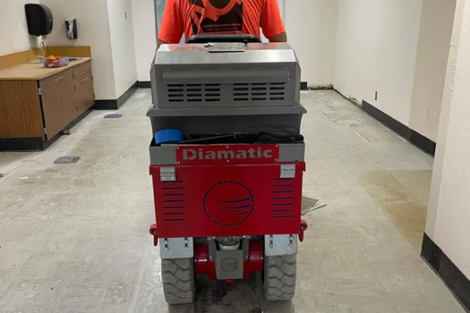 A man is driving a diamatic machine down a hallway
