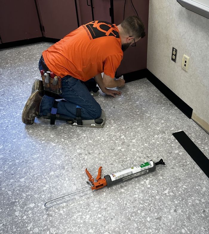 A man in an orange shirt is kneeling on the floor