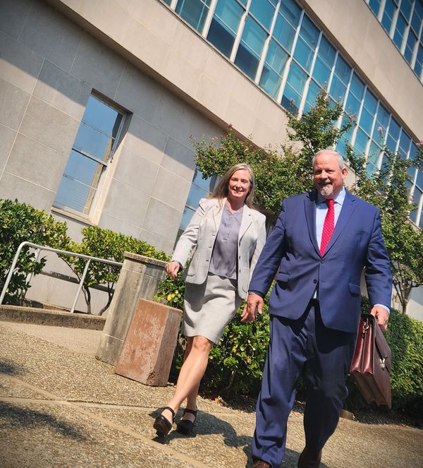 A man and a woman are walking in front of a building