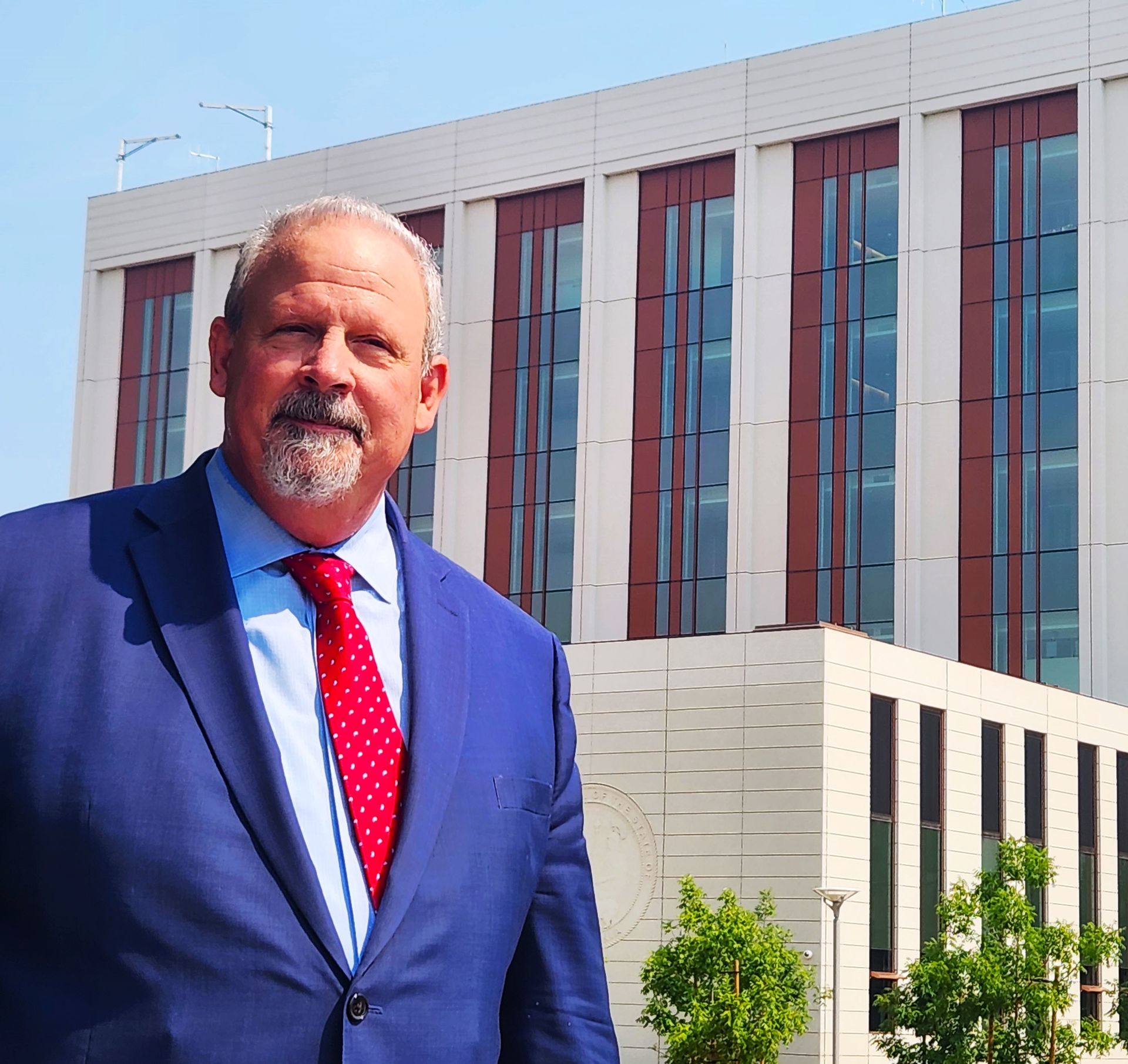 A man in a suit and tie is standing in front of a building