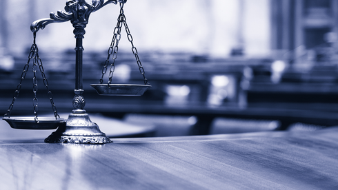 A scale of justice is sitting on a wooden table.