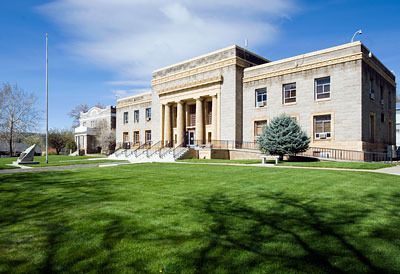 A large brick building with a lush green lawn in front of it.