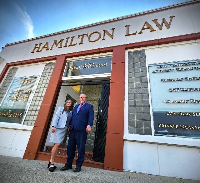 A man and woman standing in front of a hamilton law building