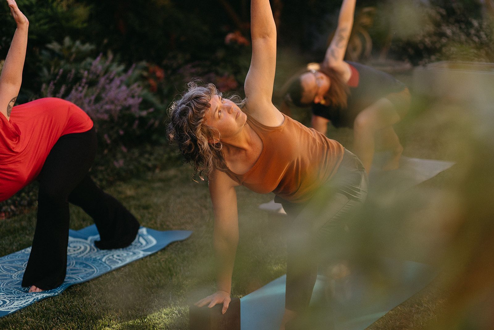 Two women are sitting on yoga mats on the floor in a gym.