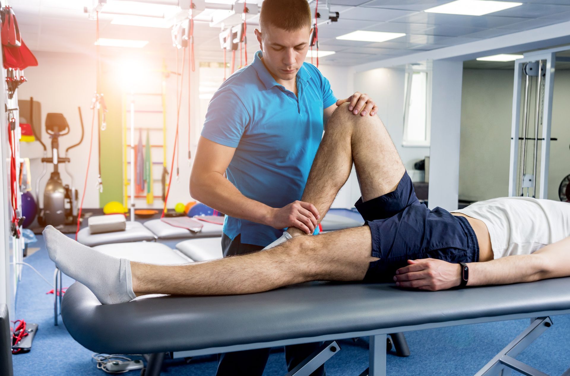 Physical therapist stretching a patient’s leg on a treatment table in a bright clinic room Physical therapist stretching a patient’s leg on a treatment table in a bright clinic room