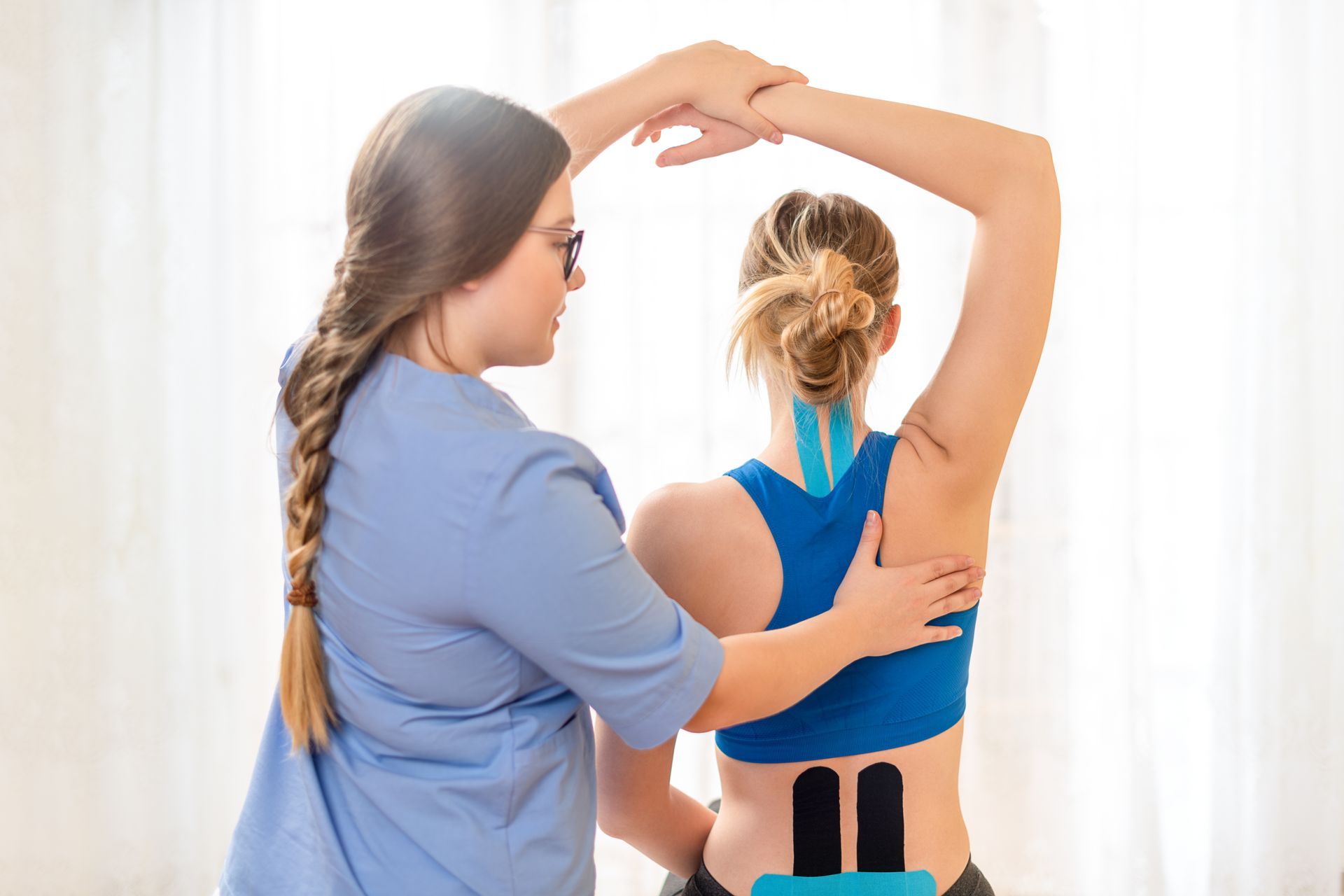 Physical therapist measuring a woman’s posture and shoulder alignment in a bright studio Physical therapist measuring a woman’s posture and shoulder alignment in a bright studio