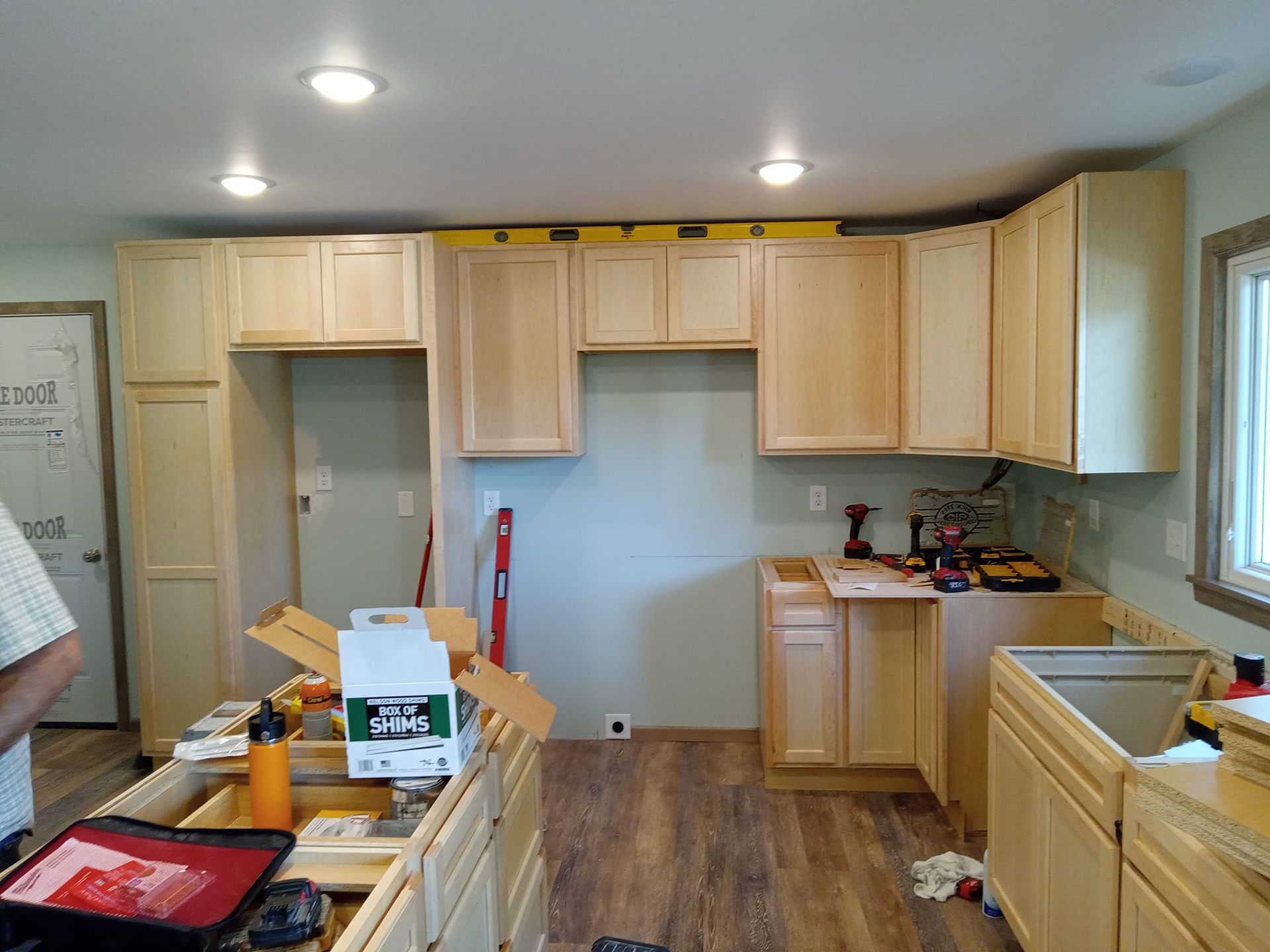 A kitchen is being remodeled with wooden cabinets and hardwood floors.