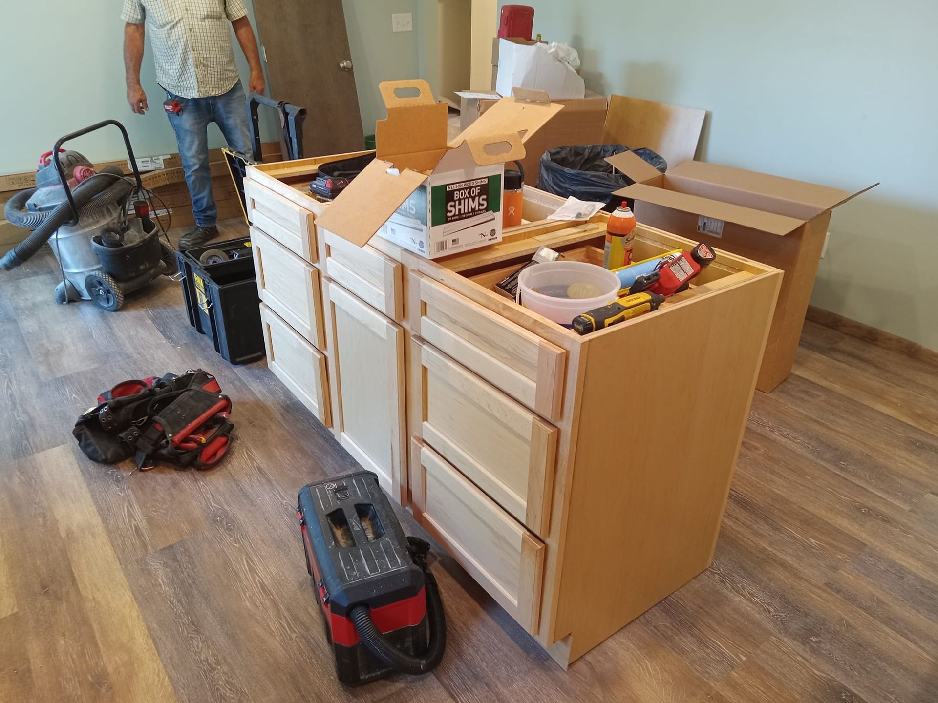 A man is standing next to a cabinet that is being built in a room.