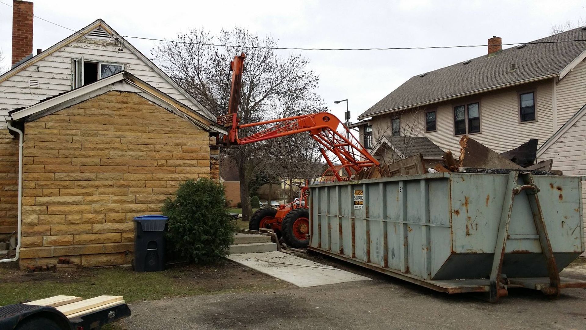 A large dumpster is parked in front of a house