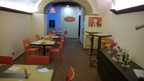 locale con tavoli scuri e sedie arancioni