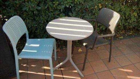 tavolo tondo da esterno vicino una siepe