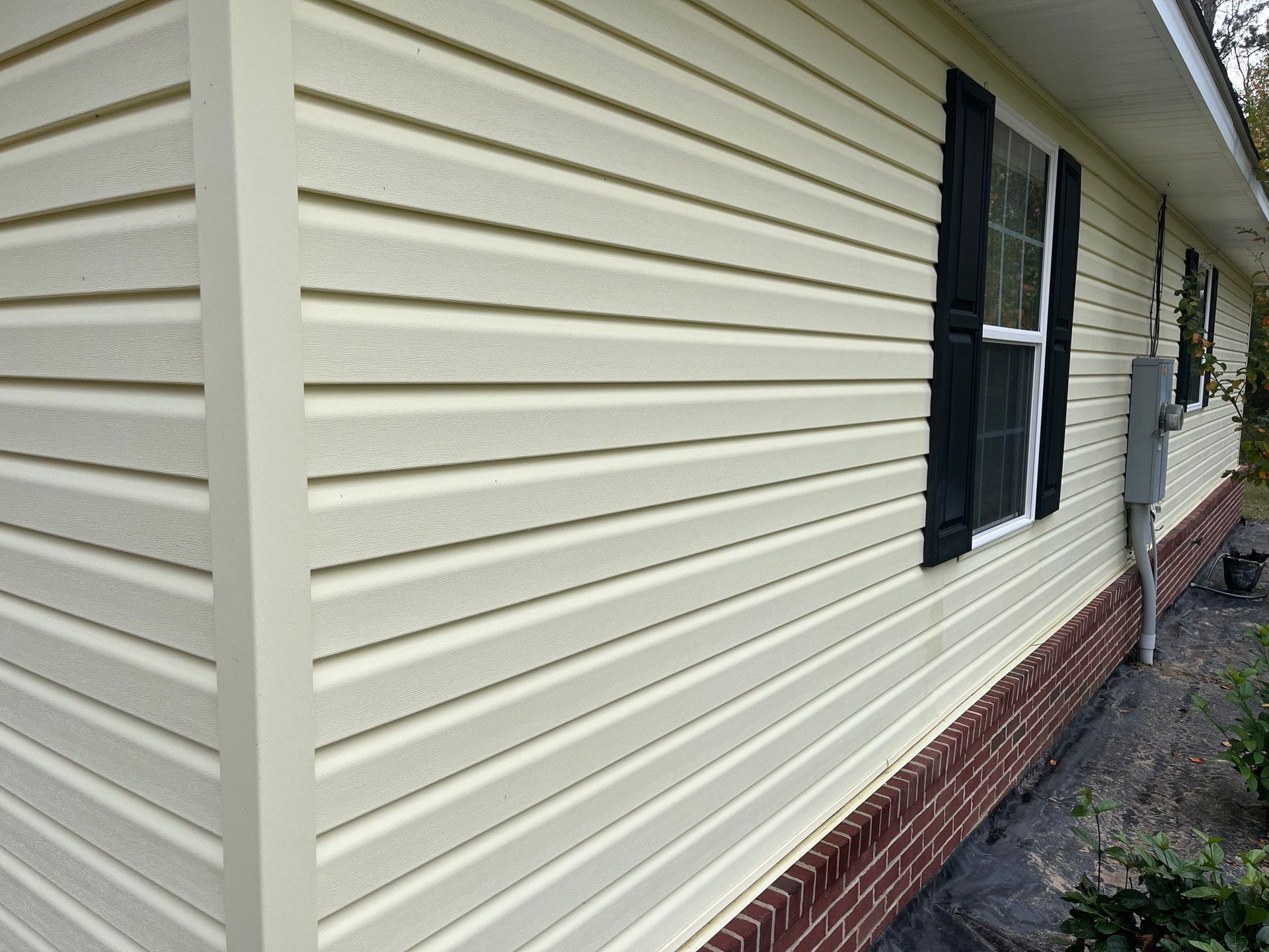 the side of a house with white siding and black shutters