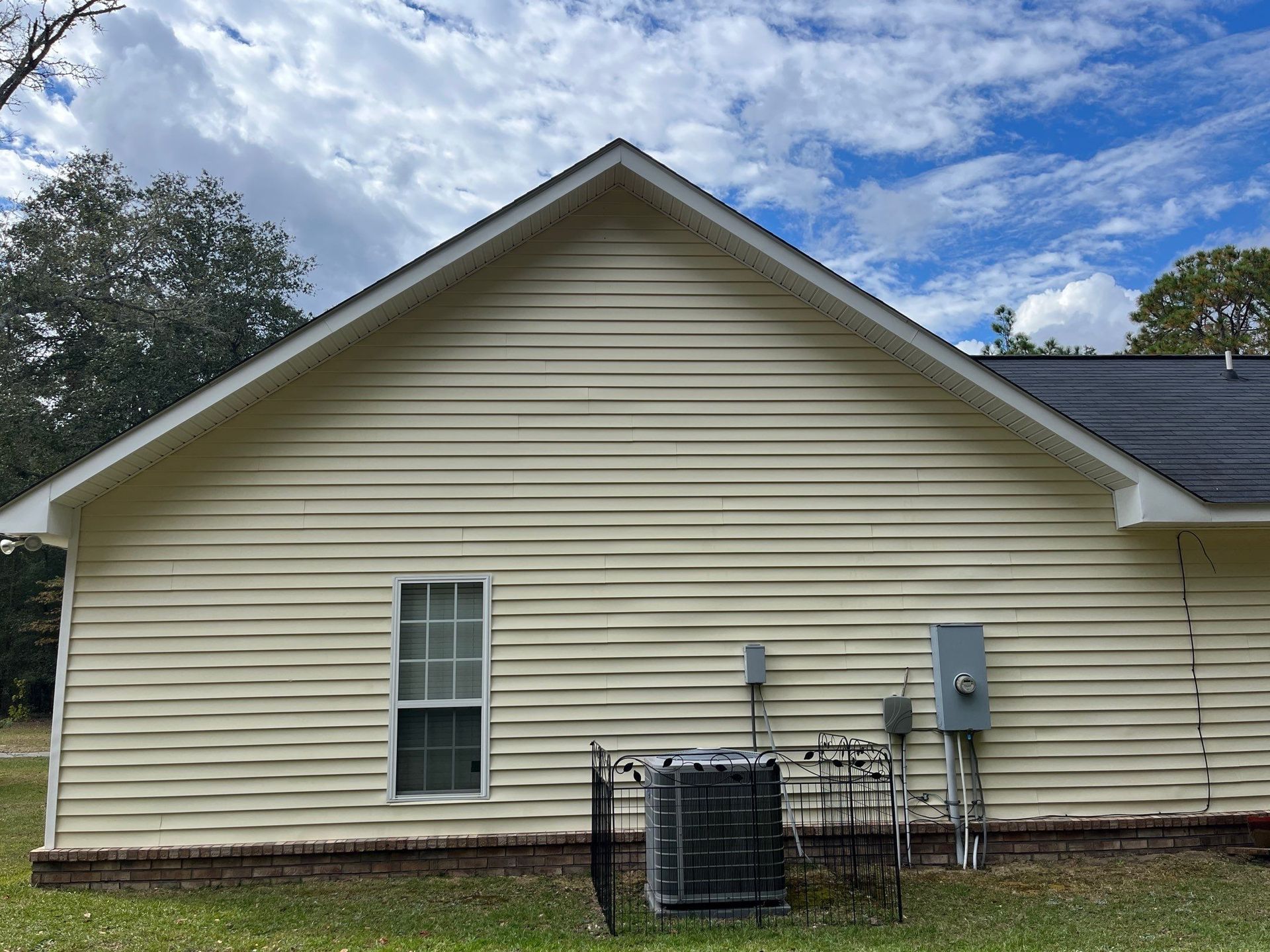 The back of a white house with a black roof and a window.