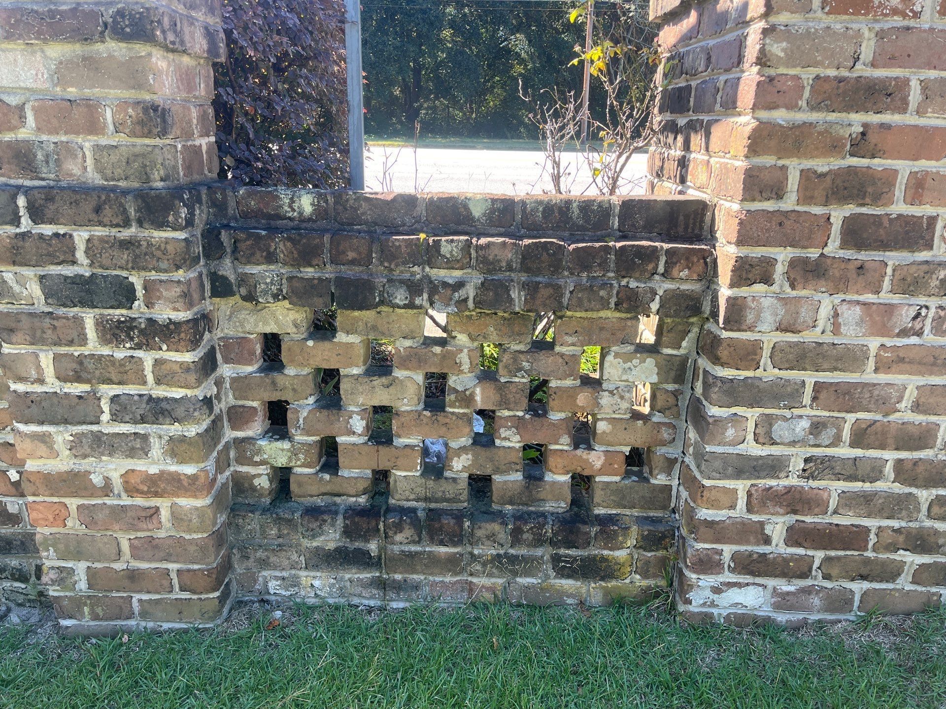 a brick wall with holes in it is surrounded by grass