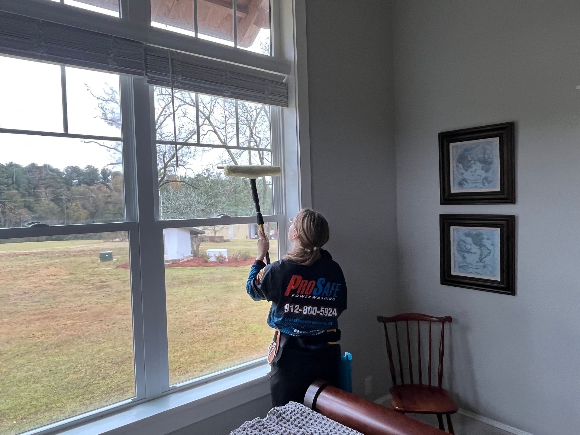 a woman cleaning a window with a prosafe shirt on