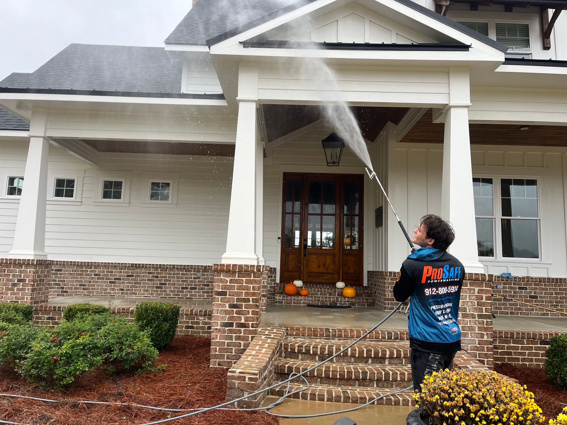a man is spraying water on a sidewalk in front of a ford truck