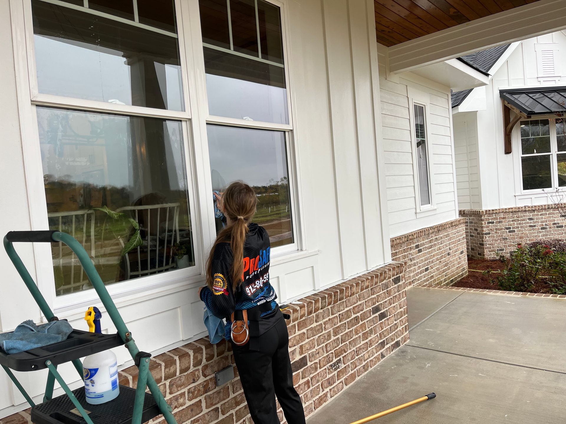 a woman is cleaning a window with a shirt that says ' a & a ' on it