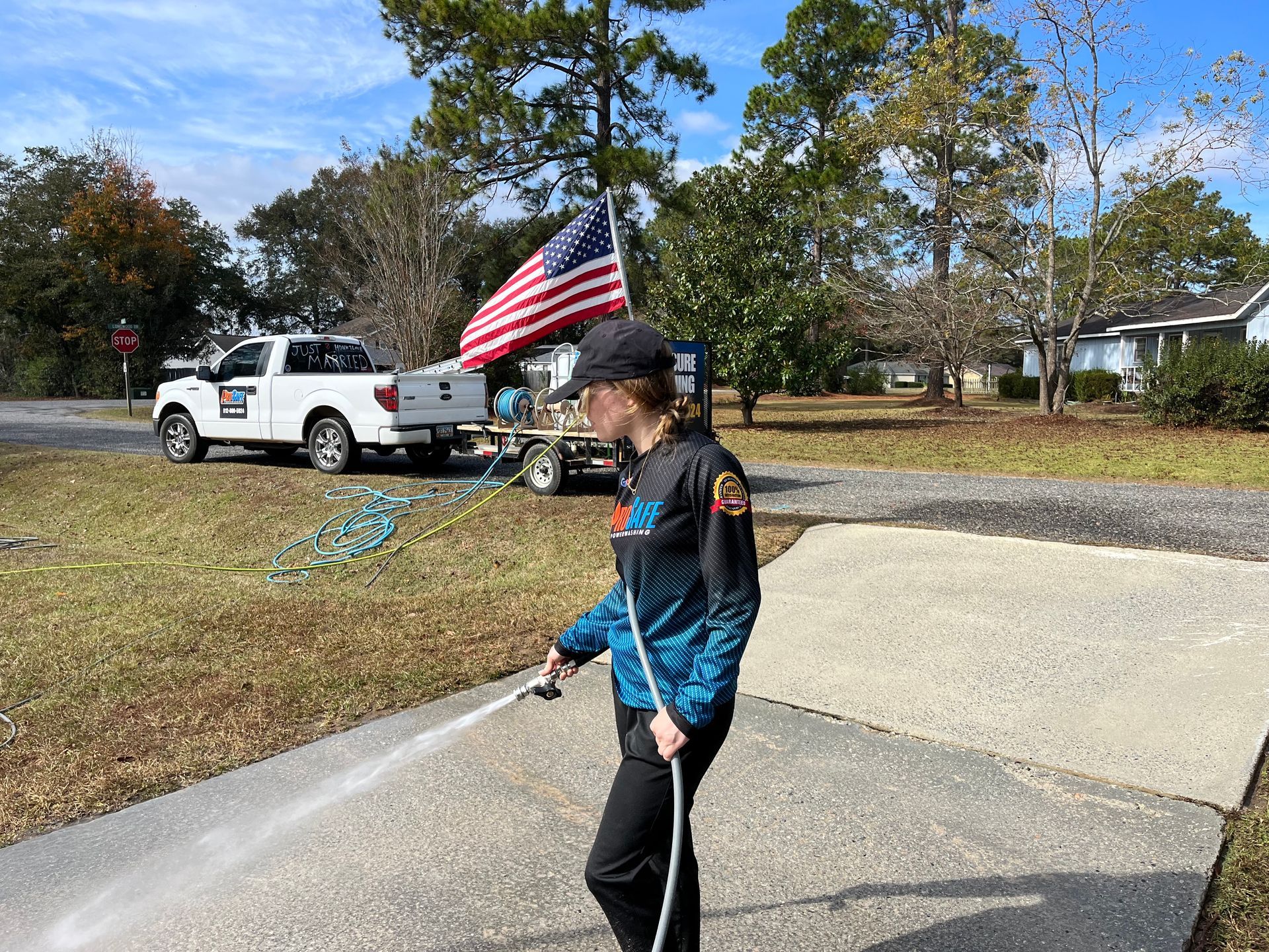 a woman is spraying water on a sidewalk in front of a ford truck