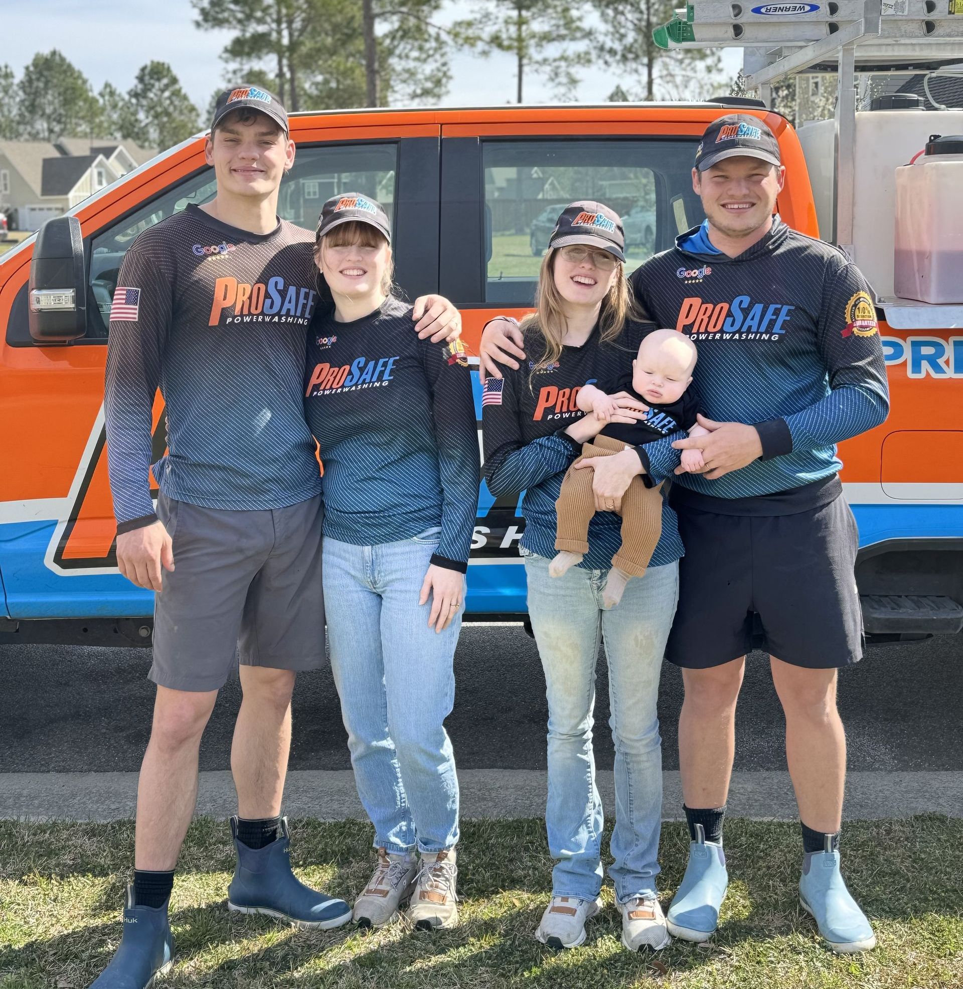 A group of people are posing for a picture in front of a truck.