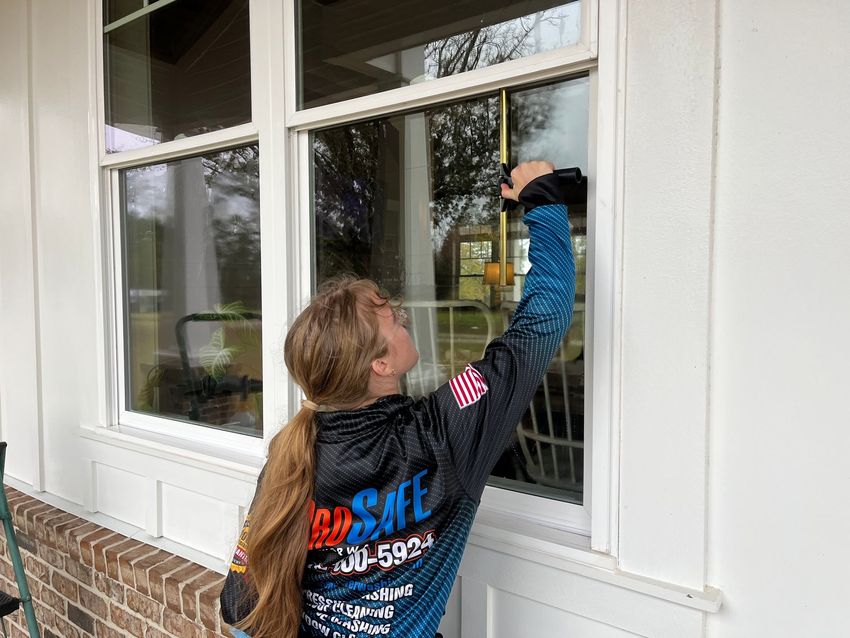 a woman wearing a shirt that says adsafe is cleaning a window