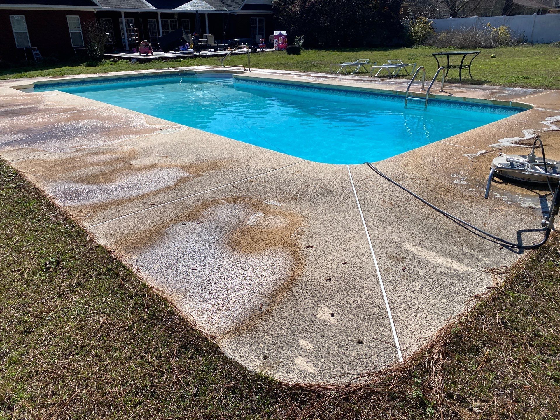 A large swimming pool is in the backyard of a house.