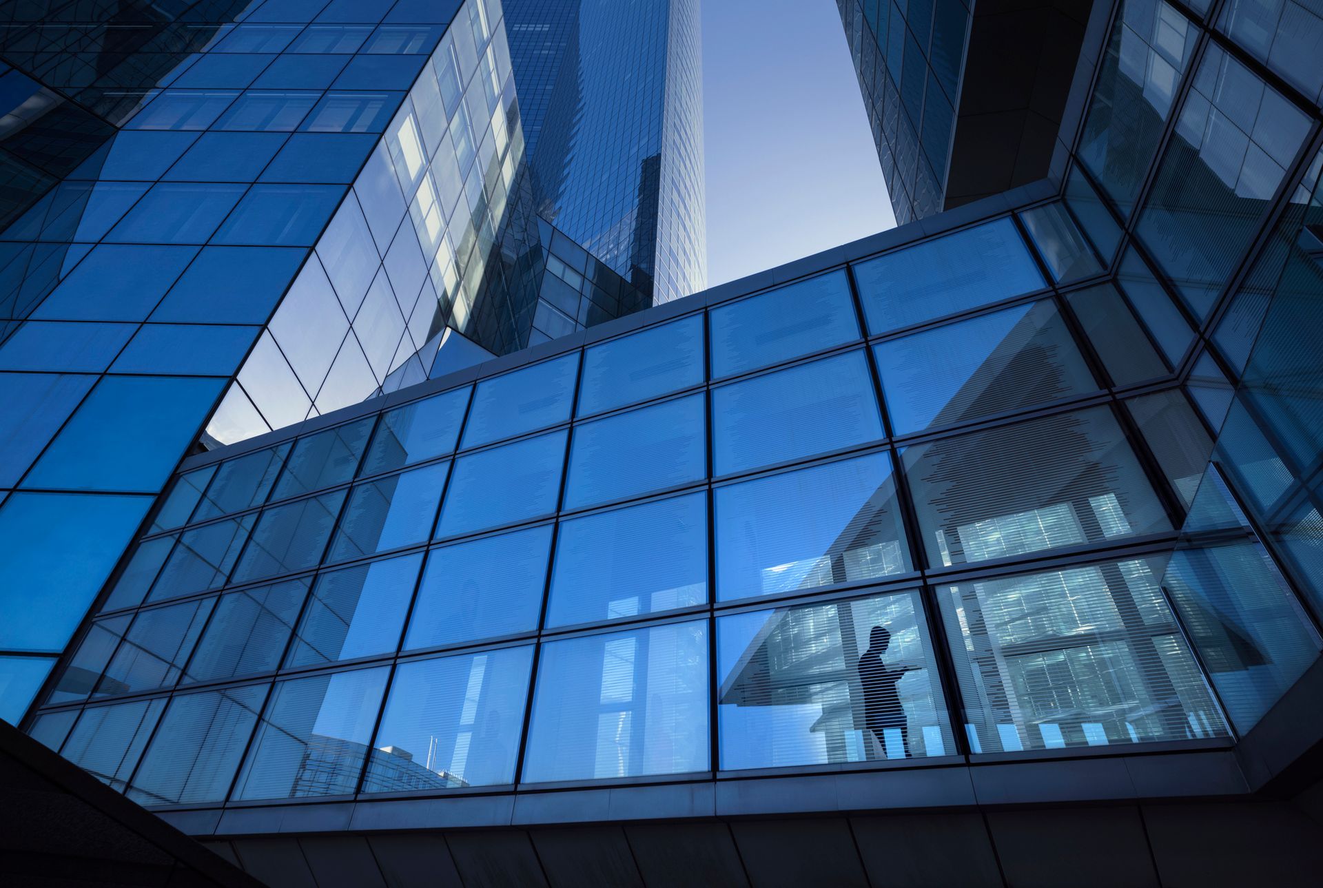 Glass skyscrapers and bridge reflecting sky, one person on bridge.