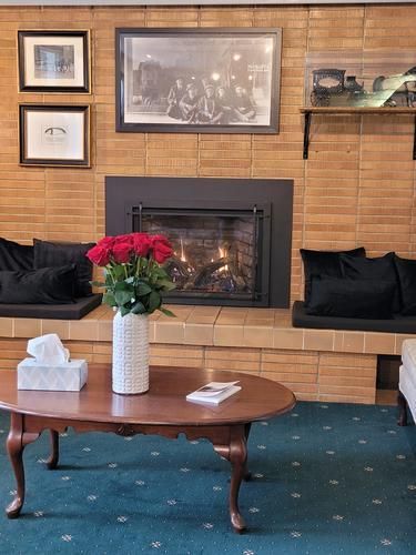 Fireplace with red roses, dark cushions, and framed photos; oval coffee table.