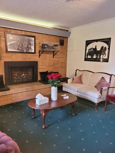 Living room with brick fireplace, cream sofa, red roses, and oval coffee table on patterned blue-green carpet.