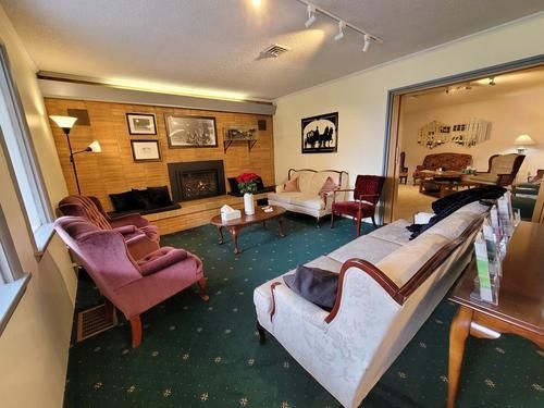 Living room with fireplace, antique furniture, green carpet, and a view into another room.