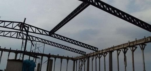 Se está construyendo una gran estructura metálica con un cielo nublado al fondo.