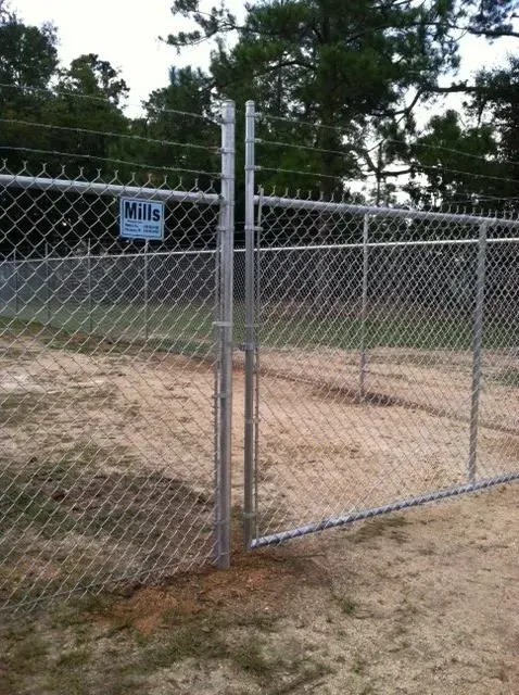 A chain link fence with a mills sign in the background