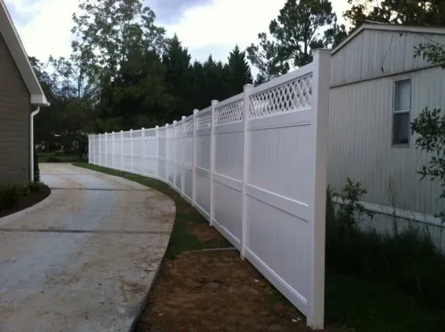 A white fence is along the side of a driveway