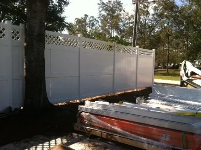 A white fence is being built next to a tree