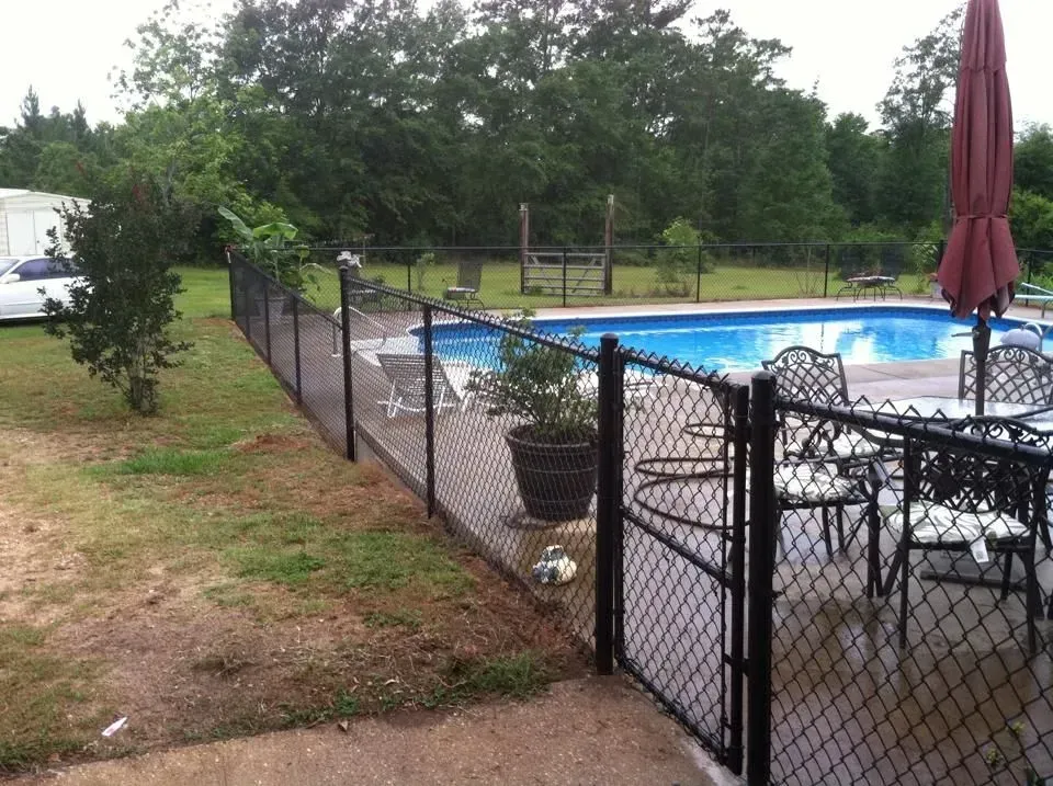 A black chain link fence surrounds a swimming pool