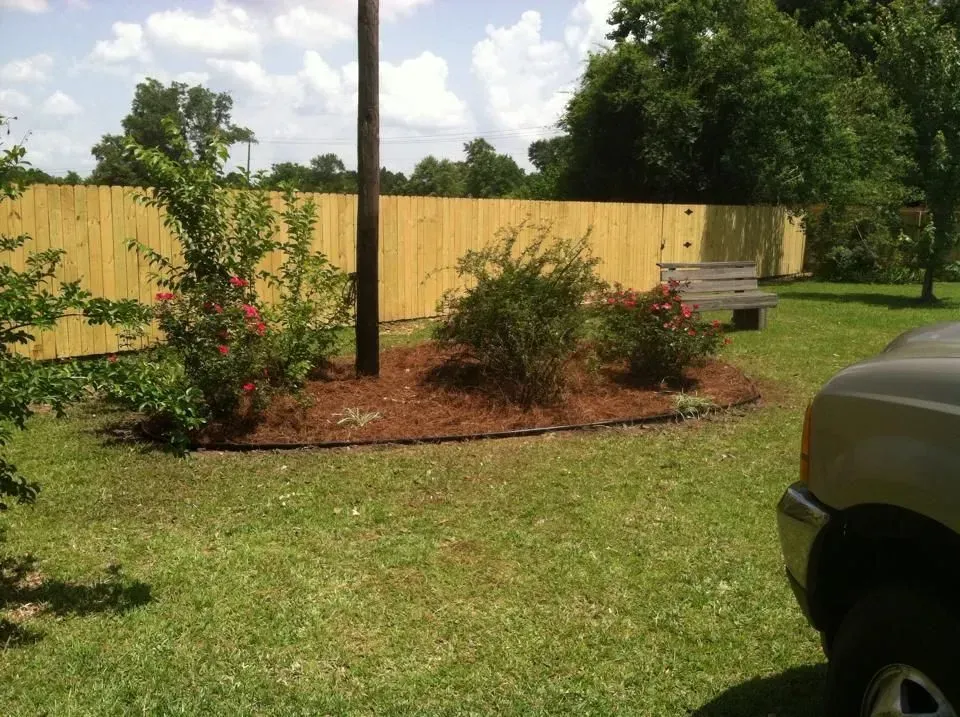A car is parked in front of a wooden fence