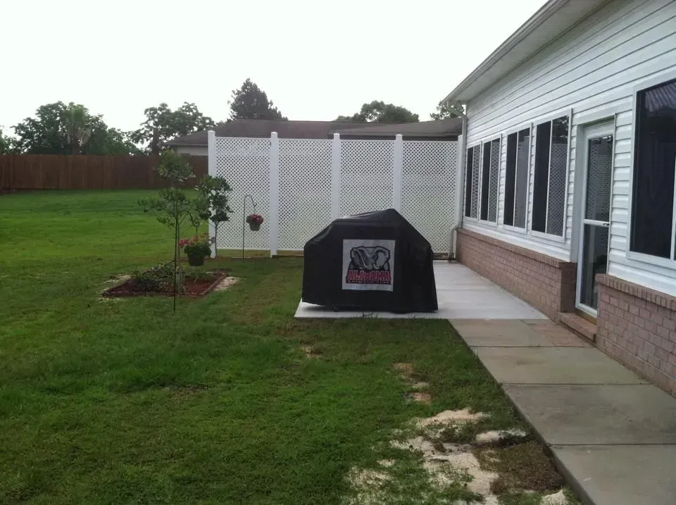 A backyard with a grill and a fence